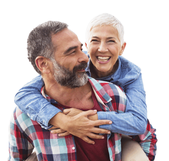 A smiling, older woman hugging an older man from behind